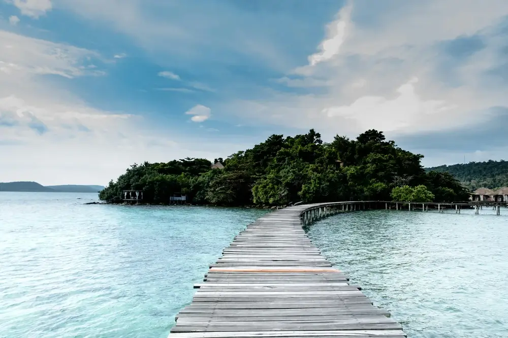 Wooden bridge leading to the green island in the middle of the water