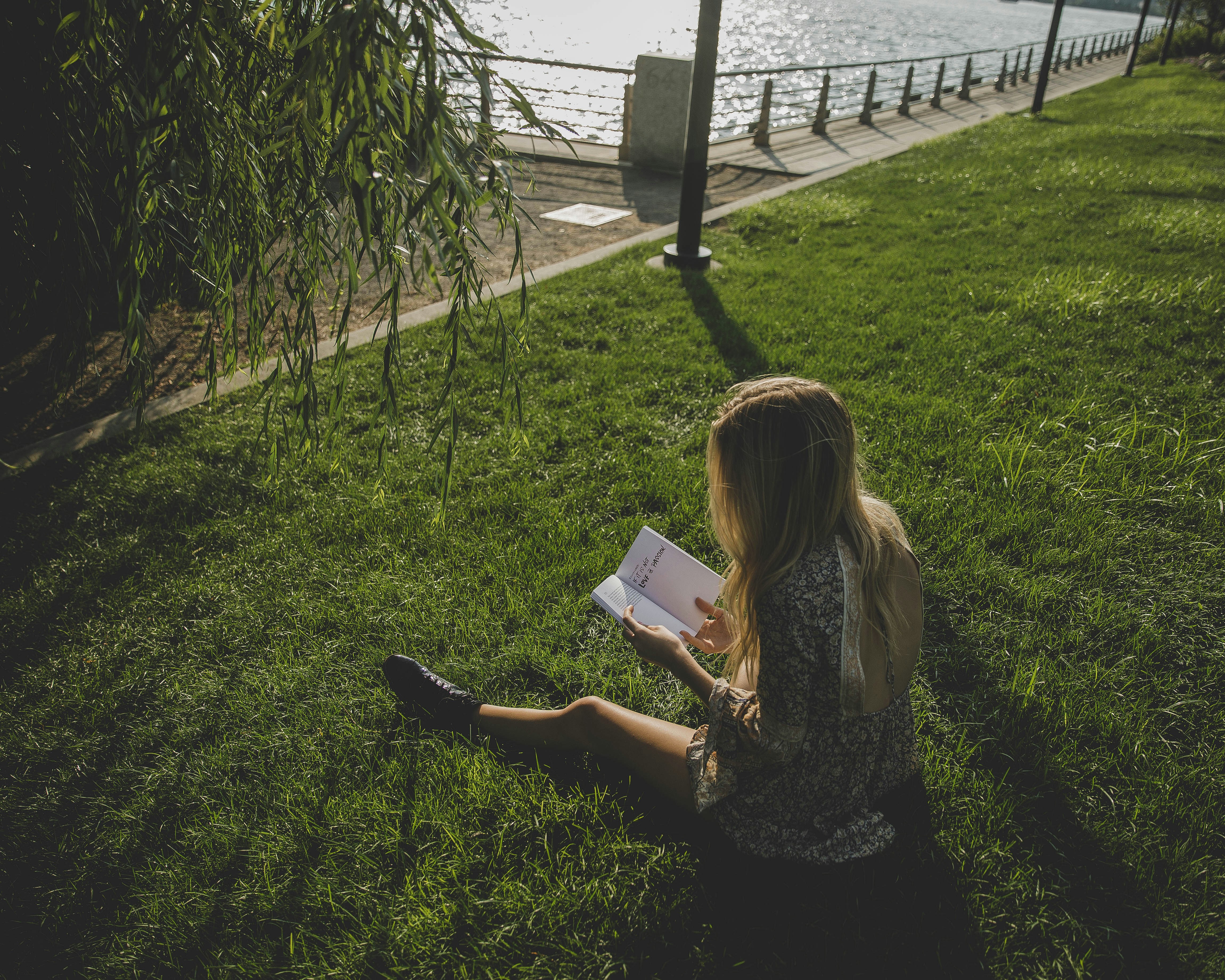 A girl is reading a book while sitting on the grass