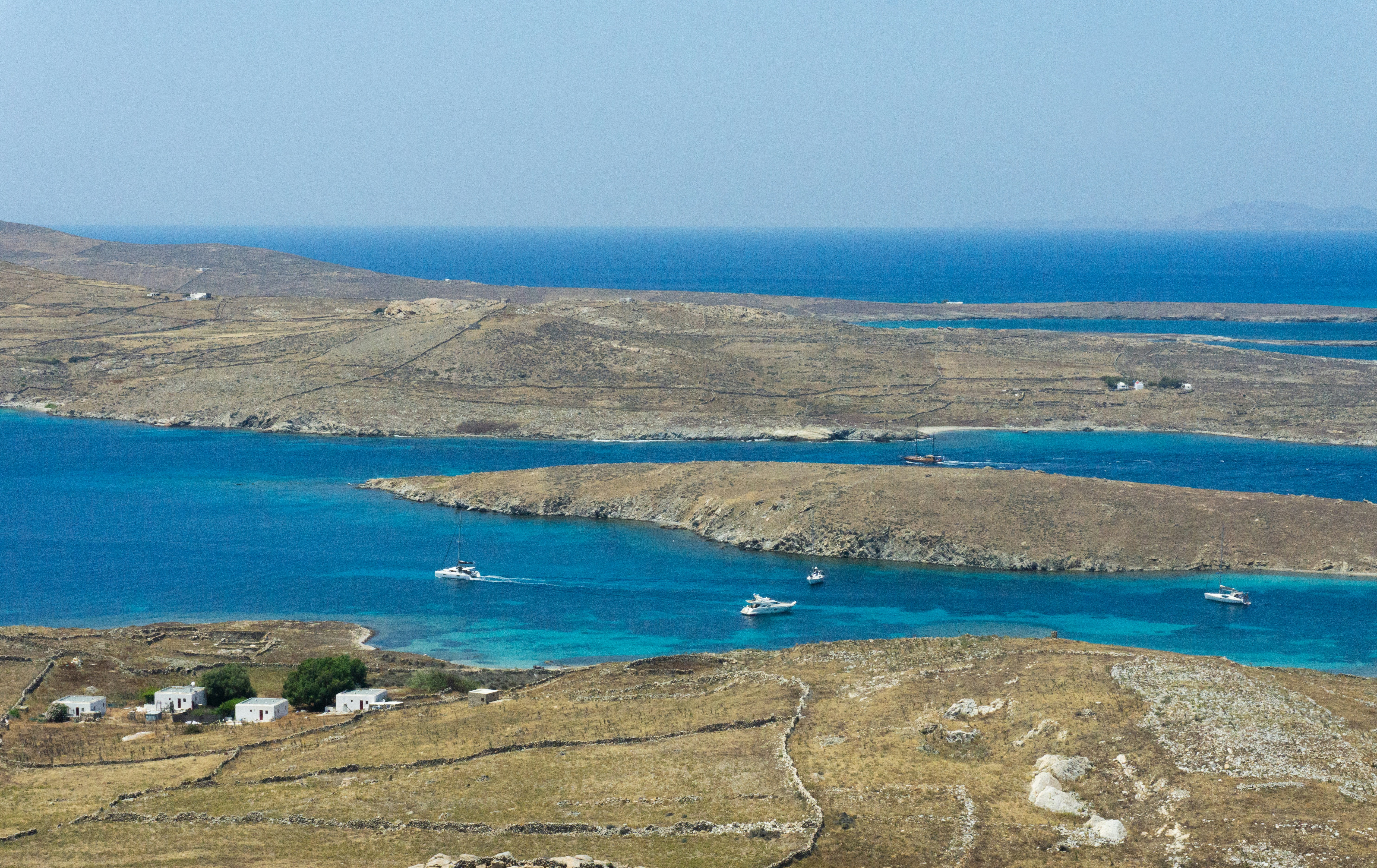 Aerial view of the island of Delos, with turquoise waters and scattered ancient ruins.