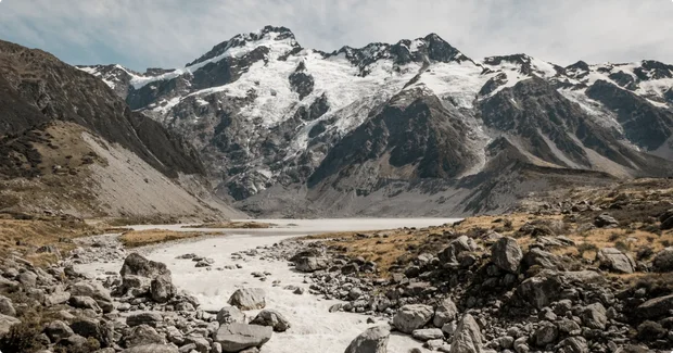 river flowing below snowy mountains