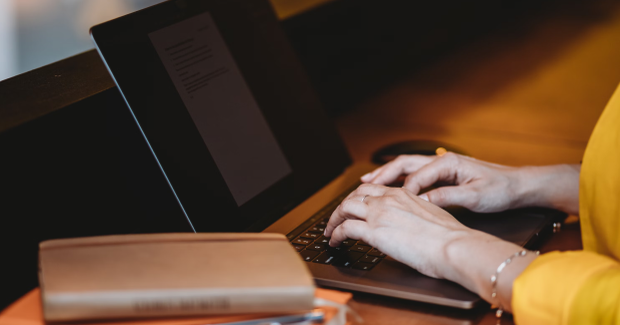 A woman is typing on a laptop