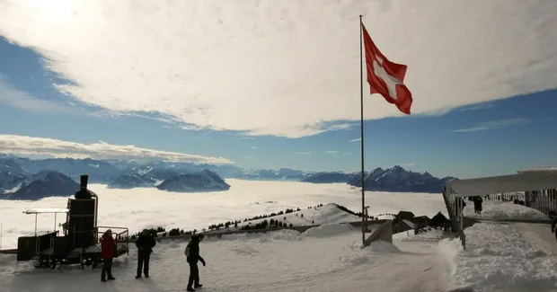 swiss flag atop a mountain