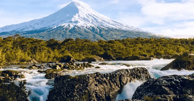 mountain covered in snow with river raging below