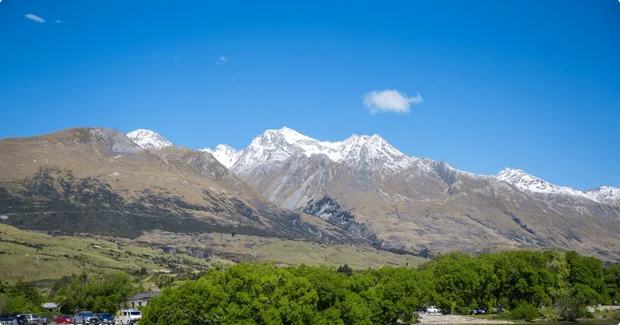 snow capped mountins with green trees below