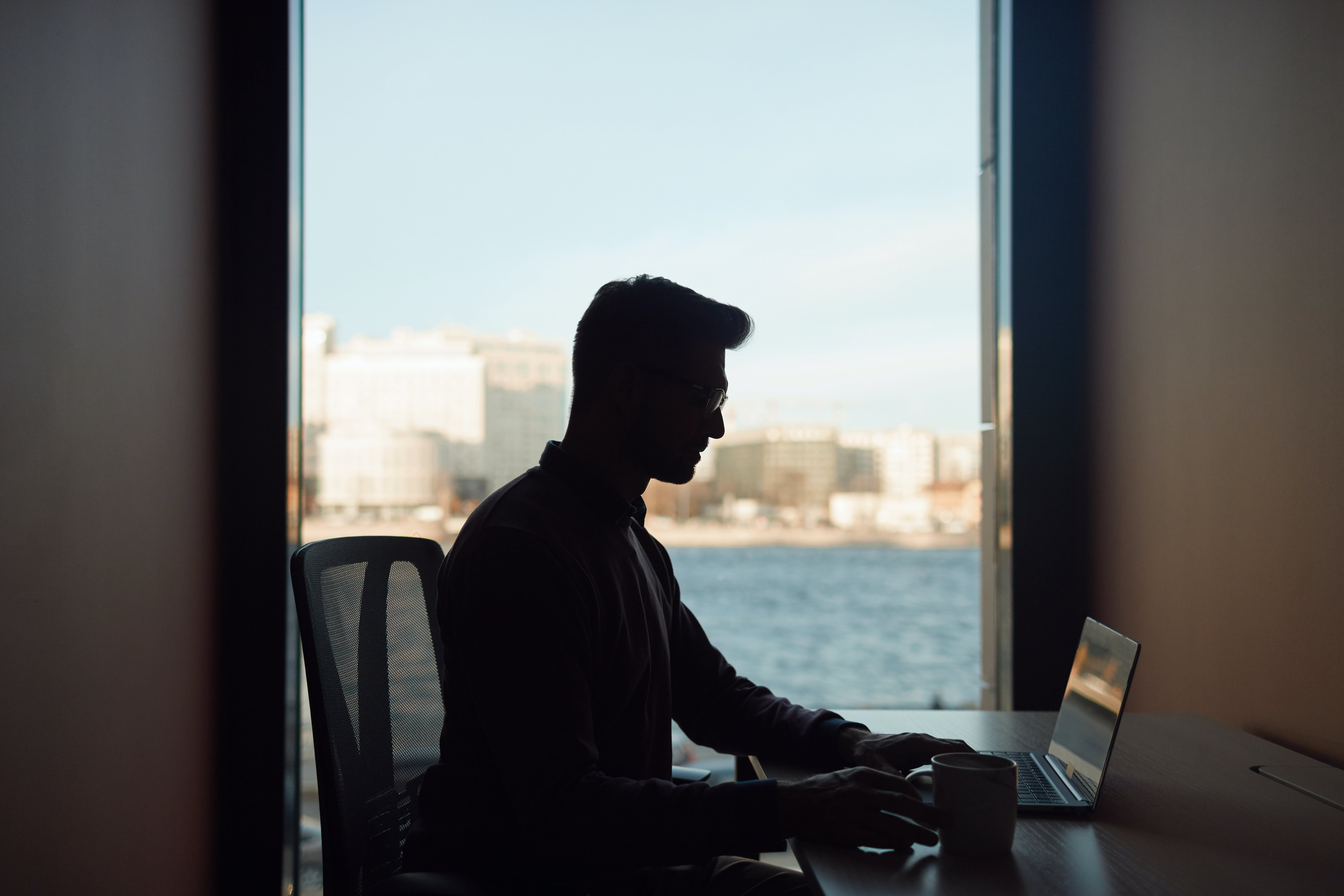 A man with a laptop by the window